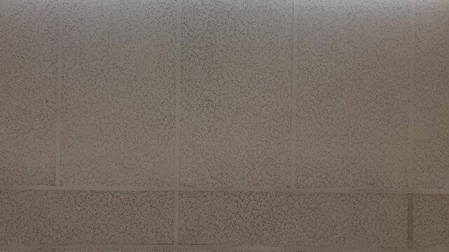 Panning shot of water damage stain on office ceiling tile with fluorescent lighting