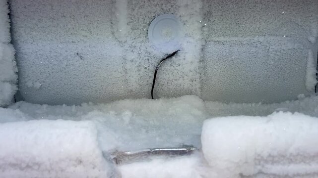 Panning shot of frost buildup inside freezer compartment