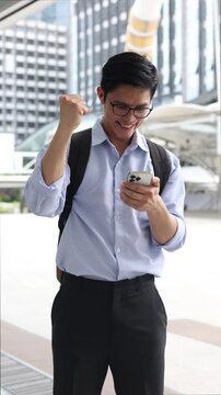 new graduated man read message from smartphone and raised hand with happiness feeling after complete and get a new job position in city for new career path concept