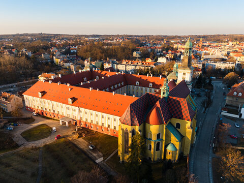 Drone aerial view of the Sanctuary of Saint Hedwig in Trzebnica, Poland, featuring the historic baroque basilica and monastic complex at sunset.