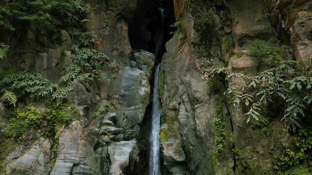 Salto do cabrito waterfall falling into a natural pool surrounded by volcanic rock