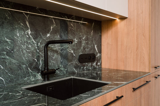 Modern kitchen features a green marble countertop with a sink and faucet