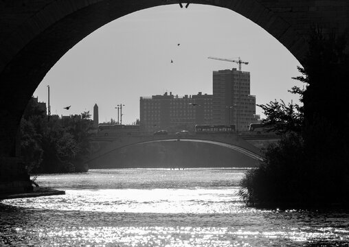 Urban landscape of Zaragoza viewed through an arch of Puente de Piedra over the Ebro River, Spain