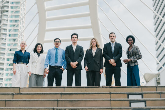 Diverse business people display teamwork and strong collaboration while standing together outdoors with professional confidence and joy