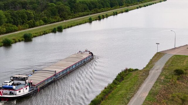 Cargo barge navigates Mittellandkanal in Germany under dramatic cloudy sky, representing inland freight transport. European waterway links major logistics routes toward Netherlands and Poland