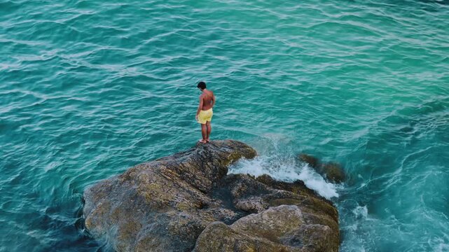 Boy jumping into the sea from a rock, blue water in the Mediterranean Greece Halkidiki