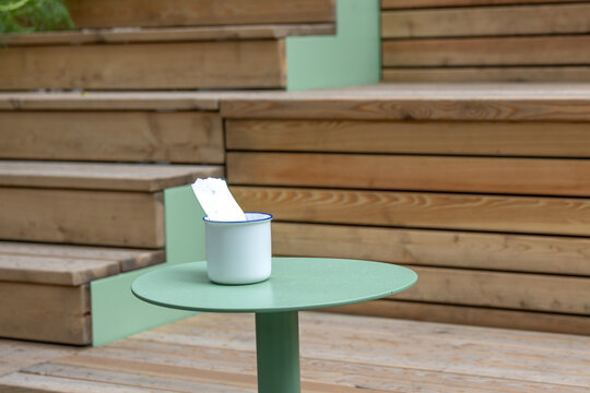 Receipt in cup on table at outdoor cafe with wooden seating during daytime