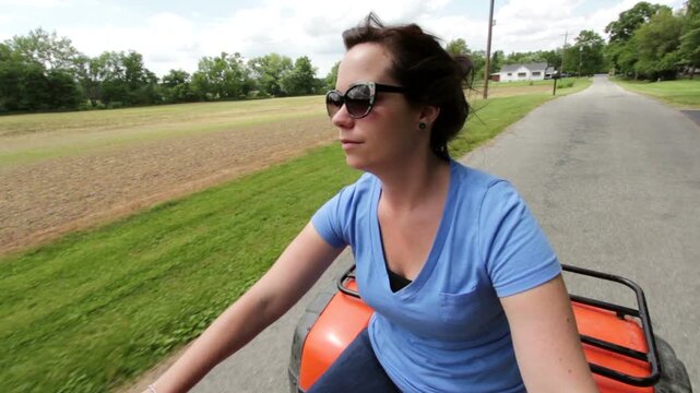 Female driving four wheeler on street
