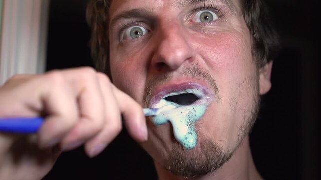 Man brushing teeth with big eyes
