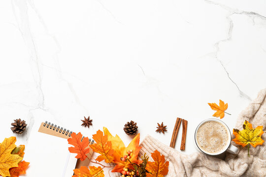 Autumn office desk. Laptop, notebook, hot tea and scarf with yellow leaves.