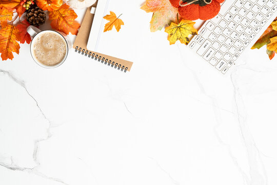 Autumn office desk. Laptop, notebook, hot tea and scarf with yellow leaves.