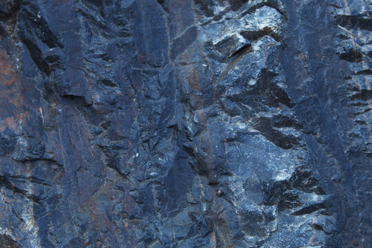 Deep blue slate rock texture with diagonal ridges and smooth fractured layers