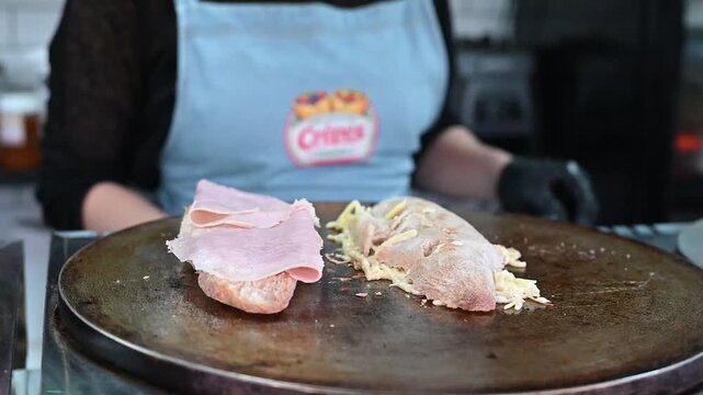 Chef preparing avocado and ham sandwich on hot griddle