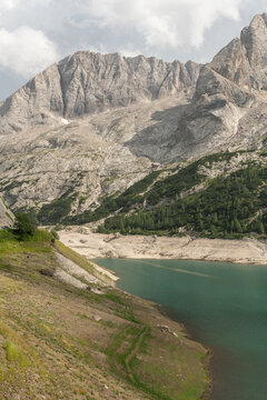 Canazei, Italy. Lago di Fedaia showing severely reduced water levels and exposed reservoir shoreline beneath the Marmolada mountains