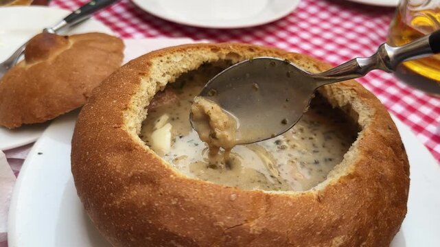 Sour cereal soup, or zurek in bread,  stirring with spoon