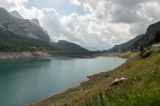 Canazei, Italy. Lago di Fedaia reservoir and dam with low water level beneath the Marmolada mountains