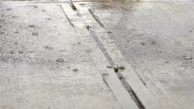 Rain drops landing on concrete in slow motion
