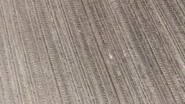 Drone Shot of Plowed Brown Field Pattern and Tire Tracks in Spring