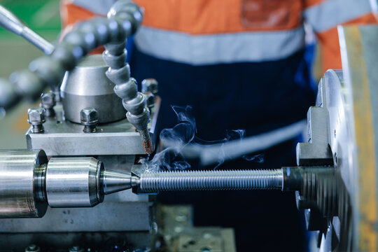 Threaded rod being machined on lathe in industrial factory workshop