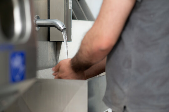 Worker Washing Hands at Industrial Hygiene Station
