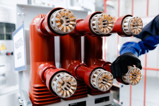 Technician adjusting high voltage connectors on electrical switchgear