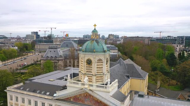Aerial view of the historic clock tower and copper dome in central Brussels, Belgium, surrounded by classical architecture and urban skyline.