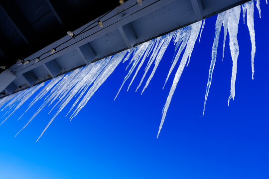 Icicles Hanging from Roof in Winter Blue Sky