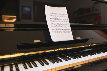 Piano with sheet music on the music stand ready for practice and piano class at home © Taras Grebinets