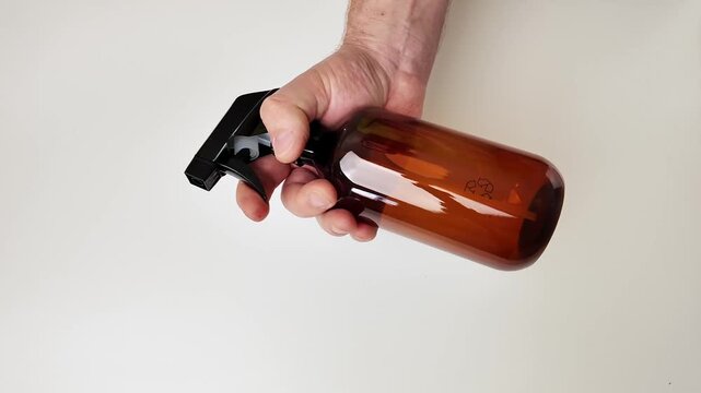 Close up shot of a hand holding a brown glass bottle against a plain light background, conveying simplicity and natural products appeal, perfect for artisanal goods promotion