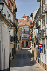 Fototapeta premium Narrow historic street with traditional whitewashed buildings, wrought iron balconies and tiled roofs in Baeza, Andalusia, Spain