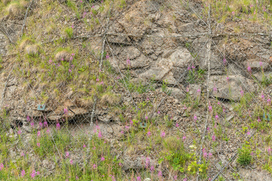 Canazei, Italy. Rockfall protection netting stabilizing a steep alpine slope near Lago di Fedaia
