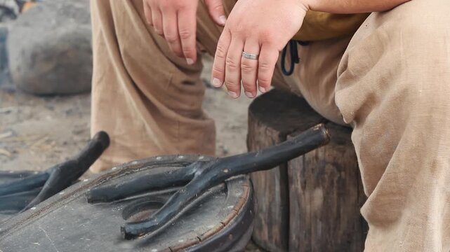 Hands of a medieval blacksmith pumping traditional double bellows to blow air into the forge fire, historical reenactment