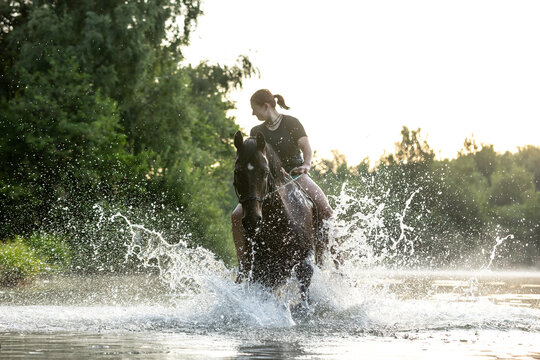 Frau badet mit Pferd im See