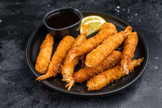 Panko fried prawns or ebi fry arranged on plate with sauce bowl and citrus wedges, crunchy deep fried seafood snack shot from above with copy space.