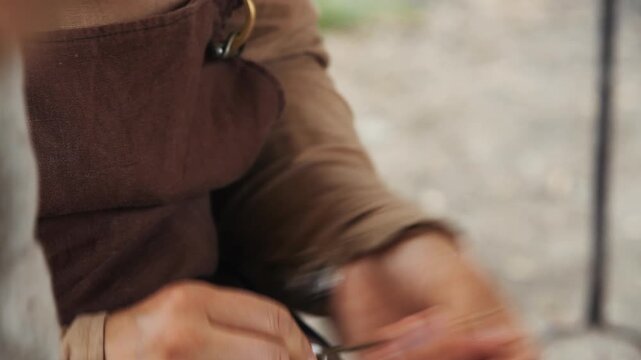Historical reenactment of artisan hand stitching fabric in traditional costume during live history demonstration