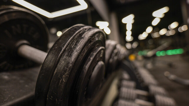 Close-up of heavy weight plates on a rack in a dimly lit gym