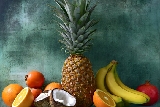 Different types of exotic fruits : pineapple, coconut, banana, orange, persimmon and pomegranate.