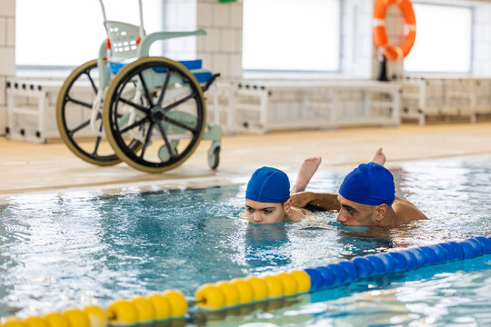 Child with cerebral palsy learning swimming with instructor