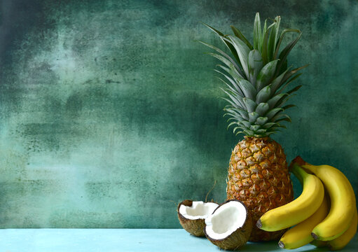 Different types of exotic fruits : pineapple, coconut, banana, orange, persimmon and pomegranate.