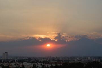 Fototapeta premium Golden sunset in Puebla with Popocatépetl’s silhouette amid clouds and warm light