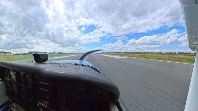 Point of view from a cockpit showing a small propeller plane taking off from an airfield runway on sunny summer day