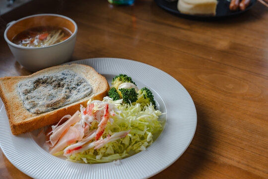 木のテーブルに並べられた朝食セット。背景には別の食事も写り込み、賑やかな様子。