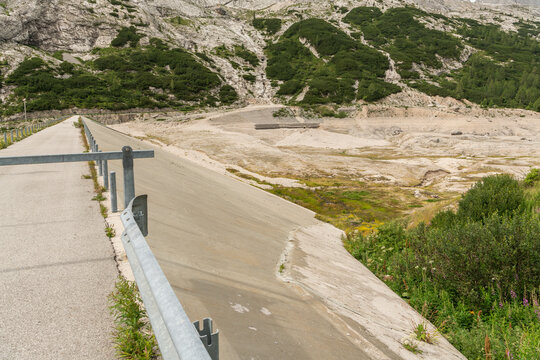 Canazei, Italy. Lago di Fedaia reservoir showing exposed lakebed and concrete dam during drought and low water levels