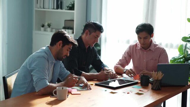 Group of diverse people sharing idea while writing at sticky notes. Professional smart business team brainstorming idea and planning strategy for startup project while wear casual outfit. Convocation.