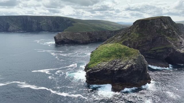 Aerial drone view of spectacular rugged sea cliffs and rocky formations near Eire 63 at Portacloy, County Mayo, Ireland. Dramatic rock formations covered with green vegetation rise from the Atlantic