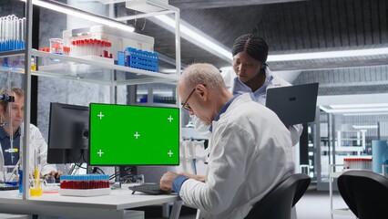 Isolated monitor mockup sits beside a diverse chemistry lab team conducting molecular science...