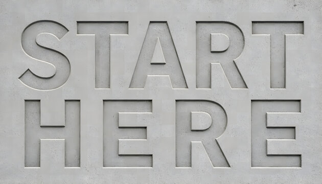 Carved letters start here in grey concrete stone wall