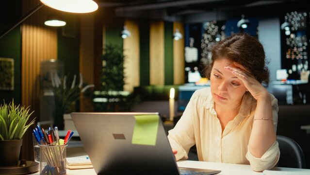 Weary employee struggles with mental exhaustion after hours showing intense workload stress fatigue and anxiety in a late-night office setting.