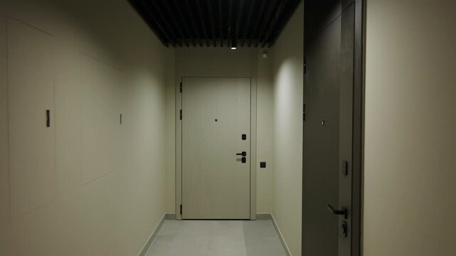 Smooth camera movement through modern residential corridor toward apartment door