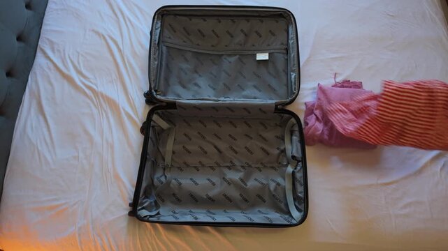 Woman picking outfits next to opened empty suitcase